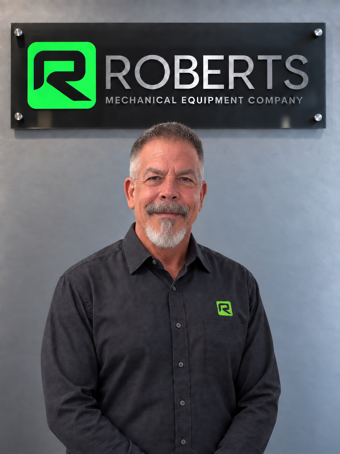 Grant Roberts, Jr. in front of the Roberts Mechanical sign